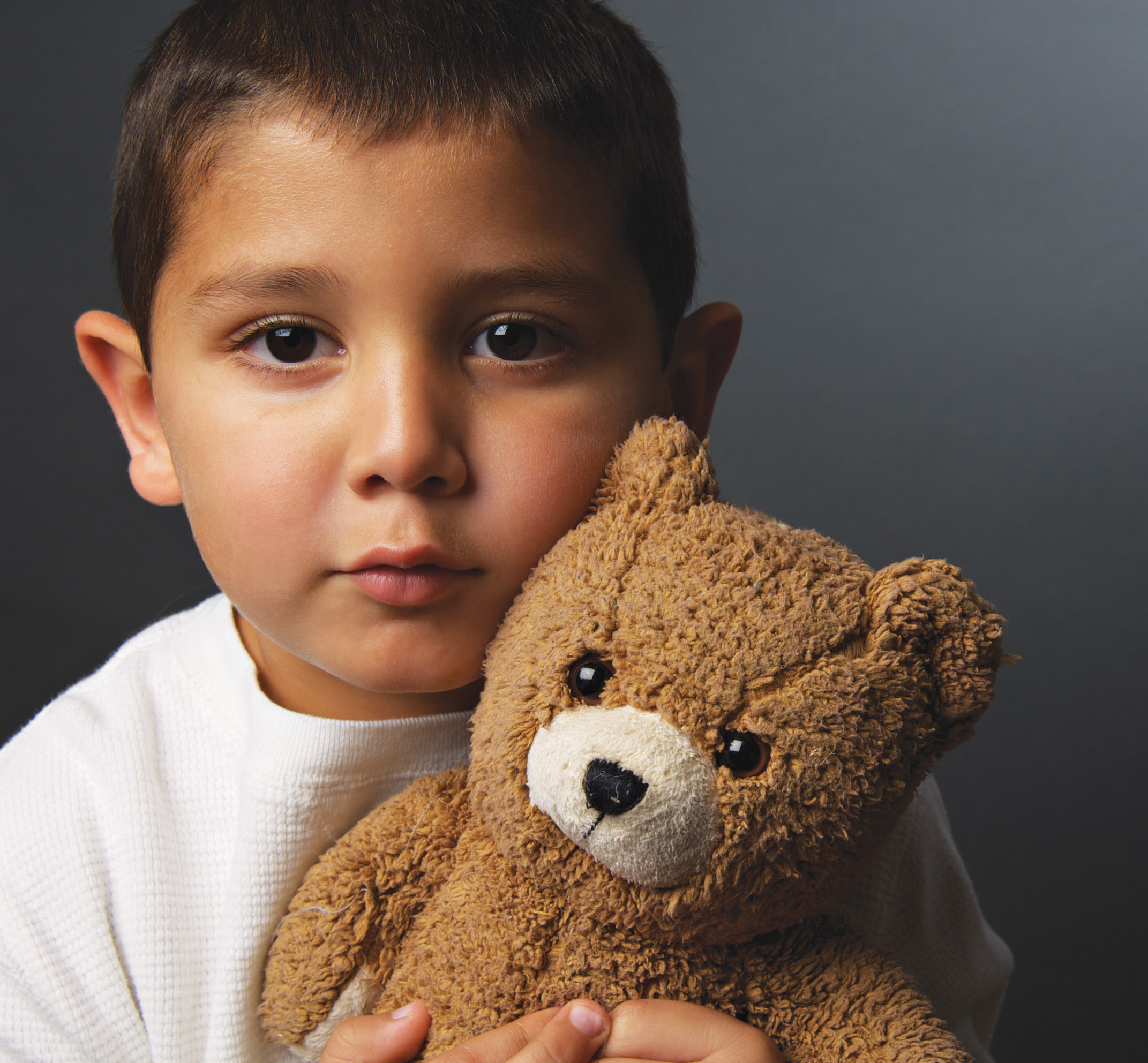 This picture is a sad boy holding his teddy bear.